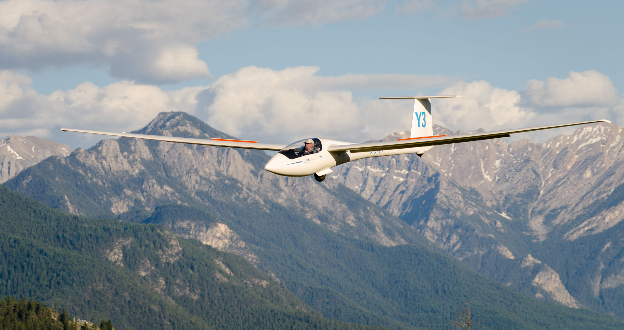 Glider gliding over forested mountain ridges